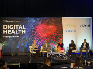 Businesspeople on stage with backdrop that says "Reuters Events Digital Health"