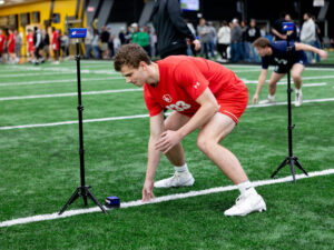 High school football players shuttle between yard lines with digital timers.