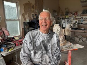 Laughing 85-year-old man in his sculpting studio.