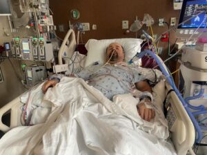 Man lies sleeping in intensive care hospital bed.