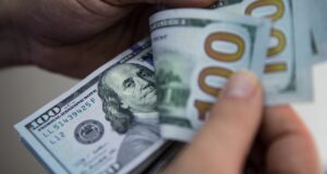 Hands flipping through stack of 100-dollar bills.