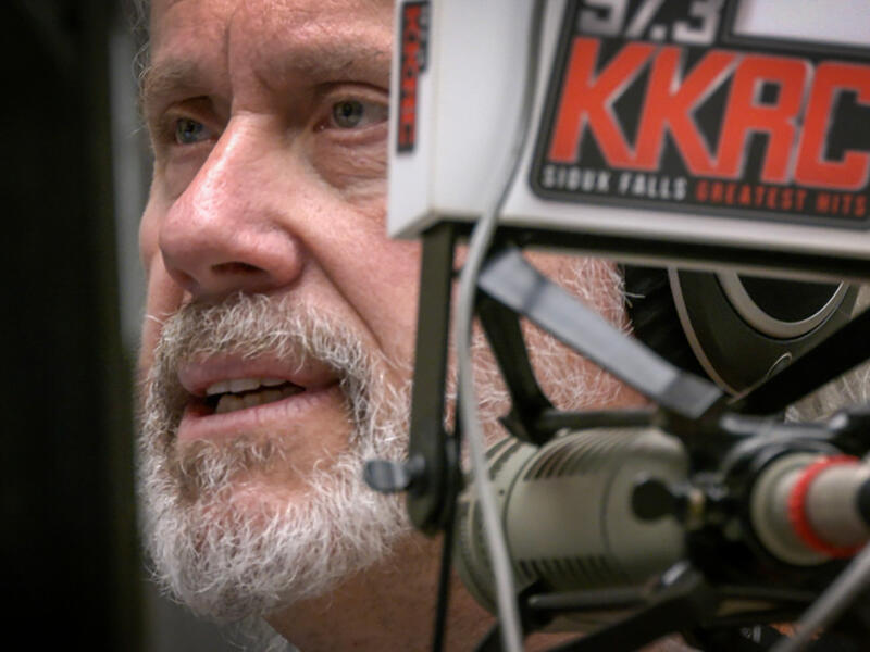 Side portrait of Alan Helgeson at radio station microphone.