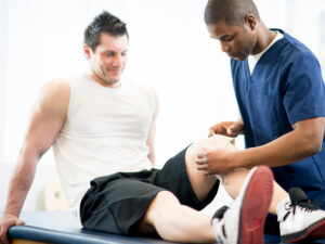 A nurse, or physiotherapist, applying pressure to a sports injury in a physical therapy clinic.