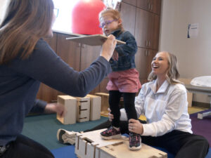 girl works on DMI therapy with women at rehab gym