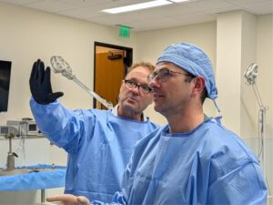 Two surgeons in scrubs look at a screen together.