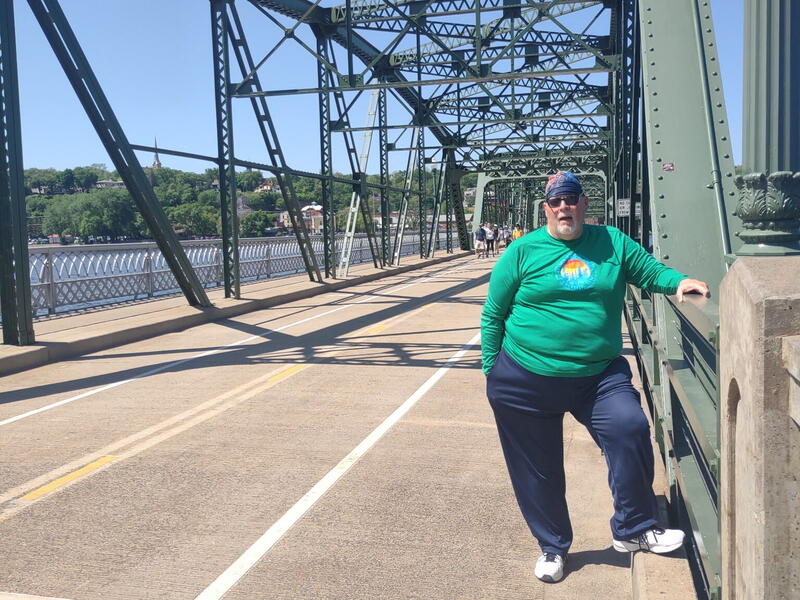 Man on a walk stops to pose on a bridge.
