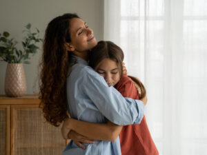 Loving mother hugging her teenage daughter at home.