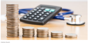 Stethoscope, calculator and stacks of coins on a desktop.