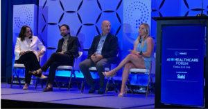 Four businesspeople sitting on a conference stage with a sign on the podium saying "HIMSS AI Healthcare Forum"