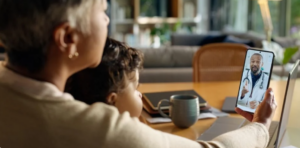 Adult caregiver and toddler talk with a doctor on a video call.